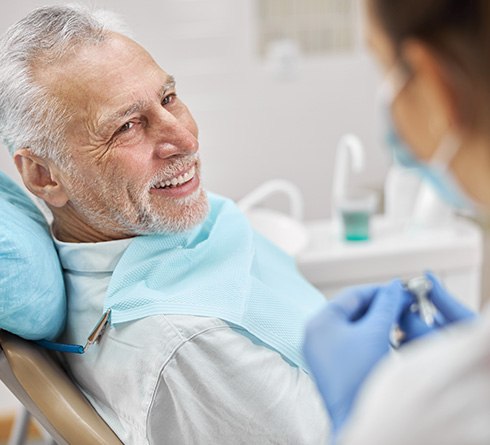 Older man speaking with dental team member