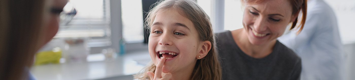 Young girl at dentist pointing to missing tooth