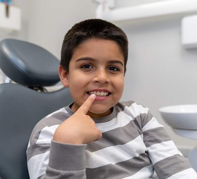 Young boy pointing to teeth at dentist