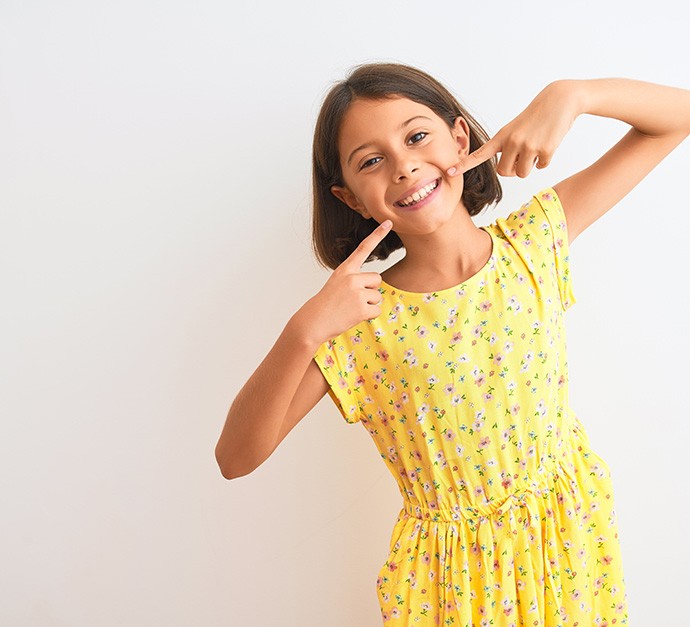 Young girl pointing to her smile